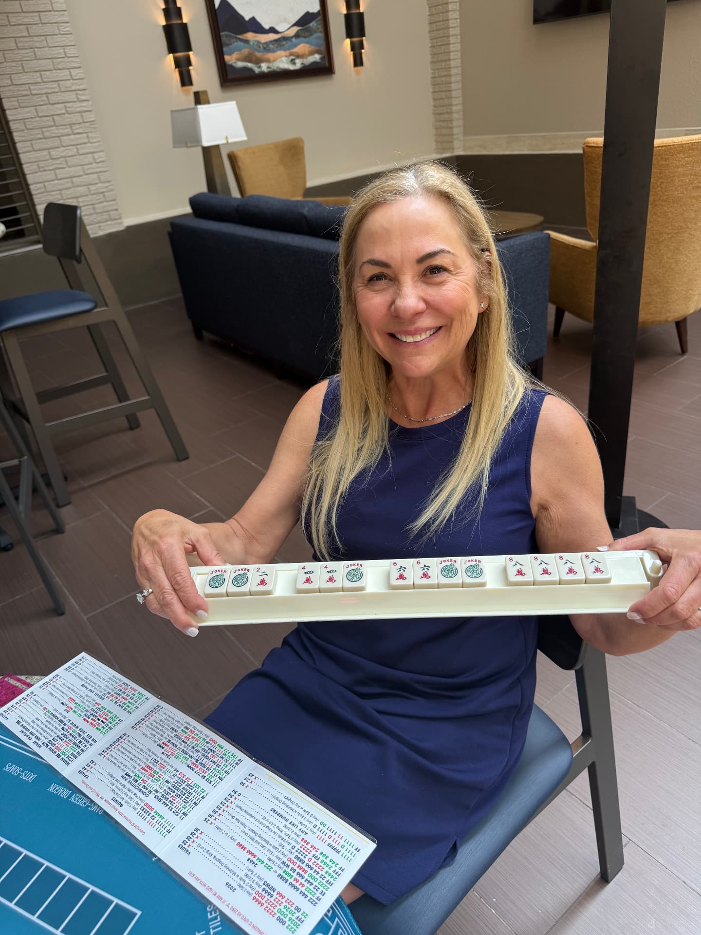 Amy Rosewater smiling and holding a rack of Mahjong tiles