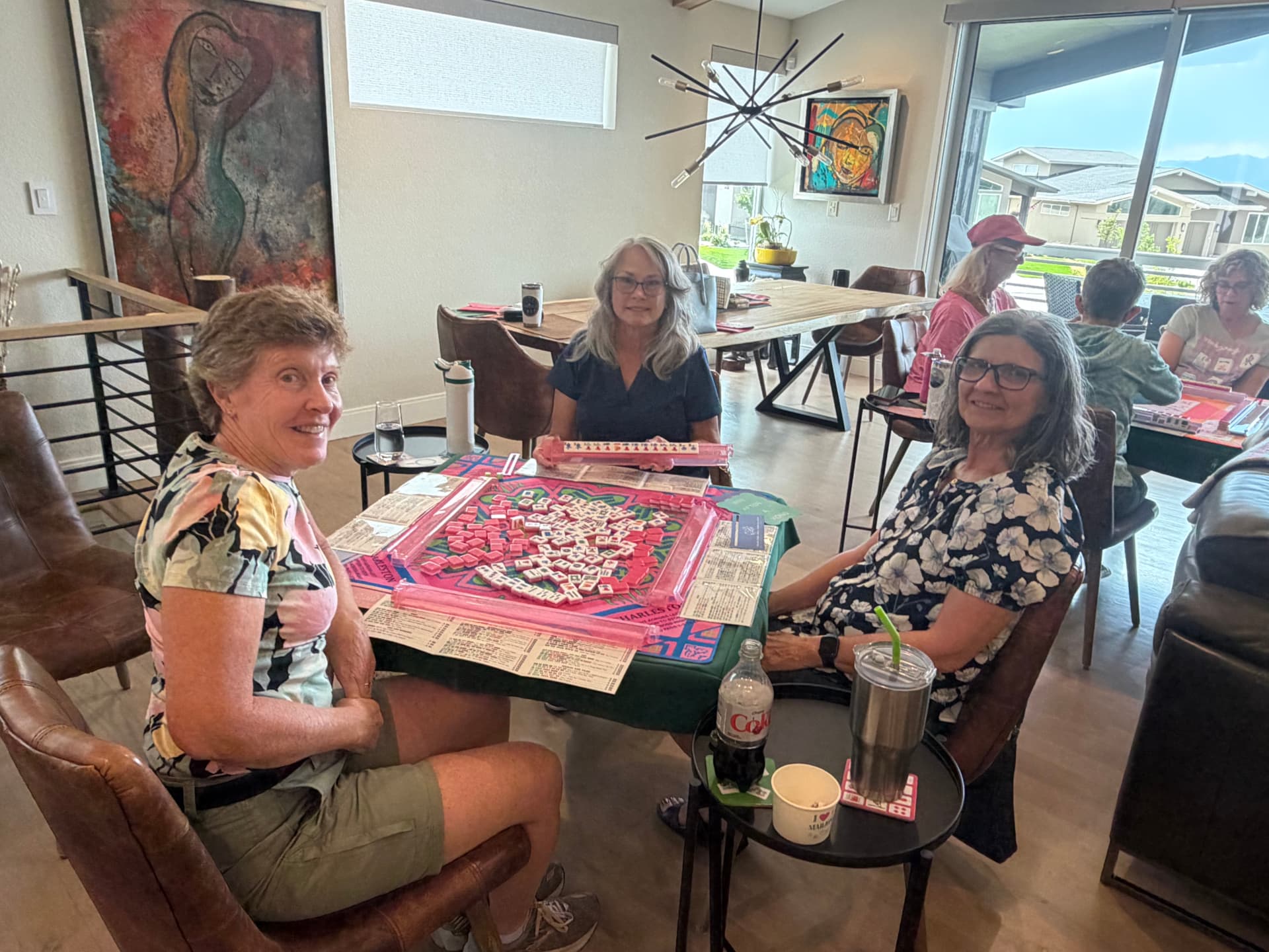 Players enjoying a game of Mahjong with pink racks and tiles