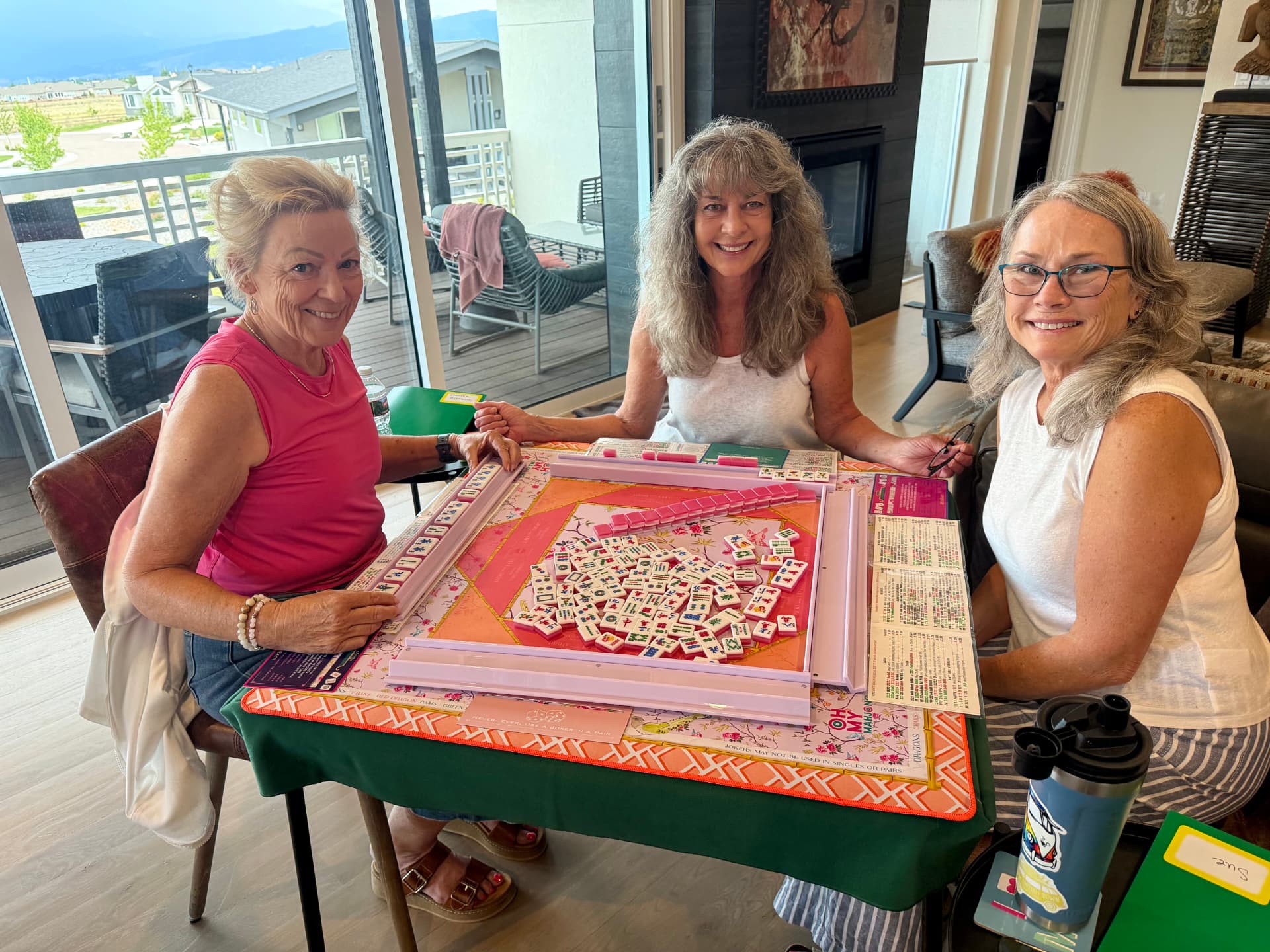 Three smiling players around a Mahjong table at Amy's Mahjong House